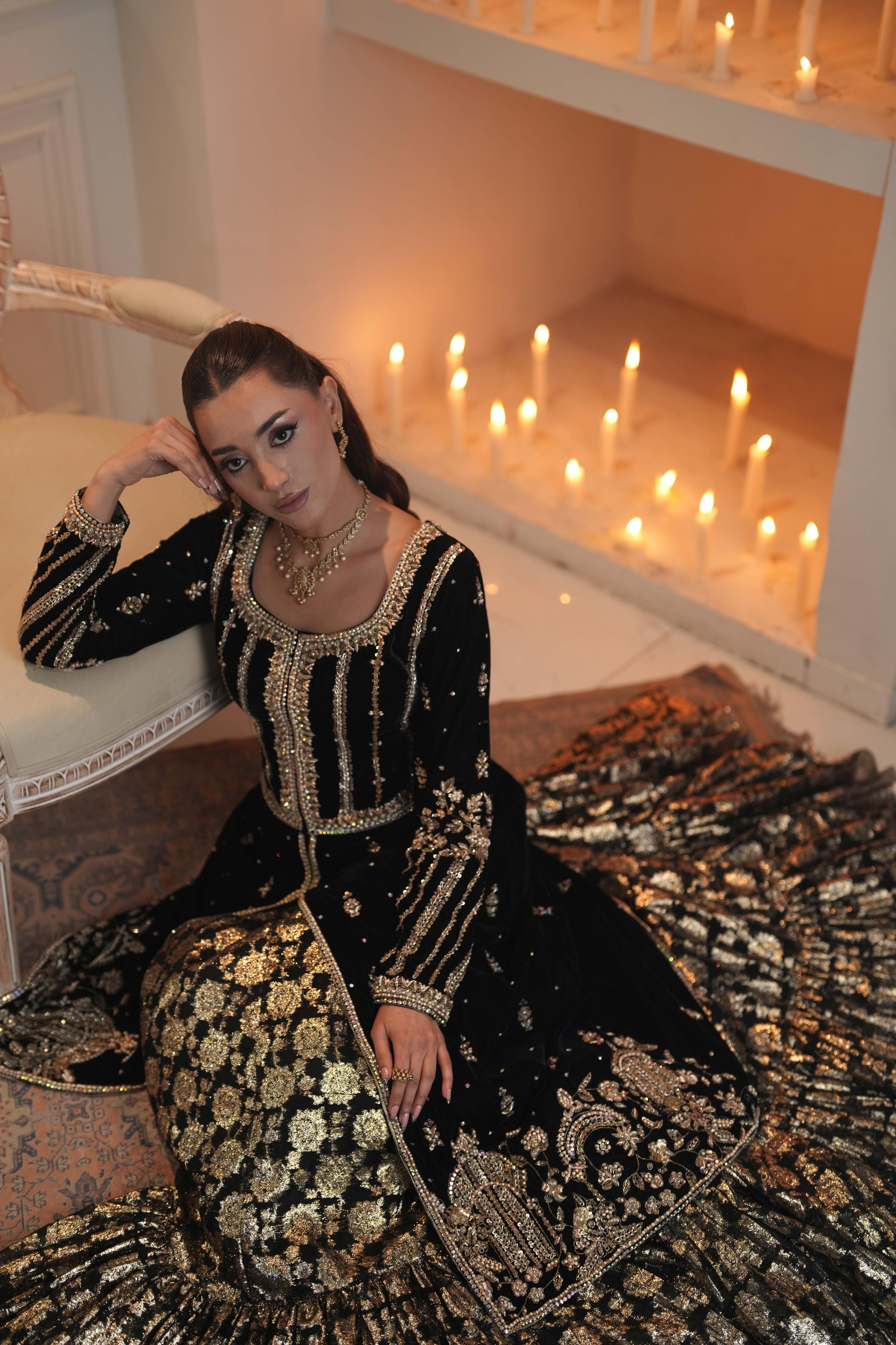 Seated front view of a black and gold bridal wear ensemble in embroidered velvet and Banarasi fabric, featuring a long